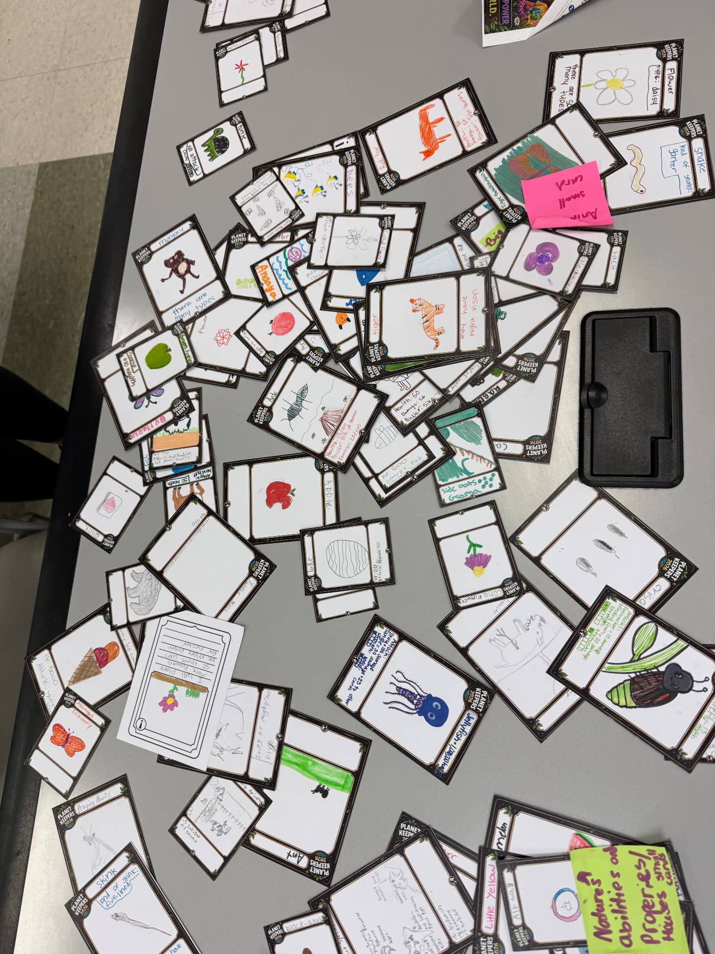 Dozens of student-drawn Planet Keepers cards spread across a classroom table
